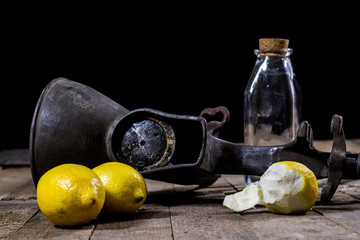 old cast iron juice machine on a wooden kitchen table. Lemon juice and squeezed lemon.