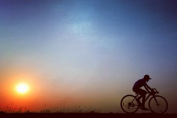 Fototapeta na wymiar Silhouette of a girl cycling a bike at the sunset time. Riding leave out the sun. Blue sky background. Minimalist style.