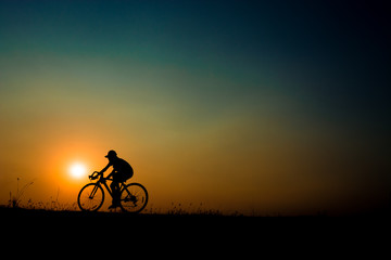 Fototapeta premium Silhouette of a cyclist riding a bicycle at sunset