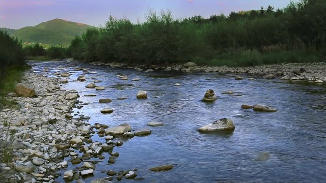 A river flows over rocks in this beautiful scene in forest mountains.