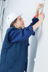 adult female constructor measuring the wall