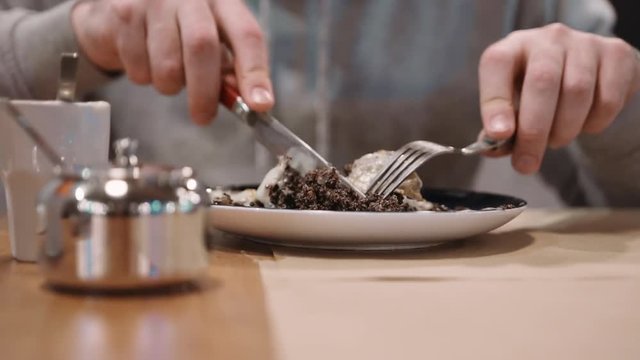 Unrecognizable girl eating dessert strudel at the restaurant using fork and knife. Close-up. Slow motion.