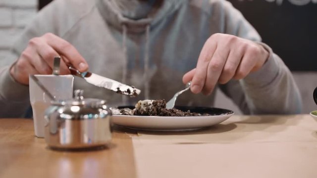 Unrecognizable girl eating dessert strudel at the restaurant using fork and knife. Close-up. Slow motion.