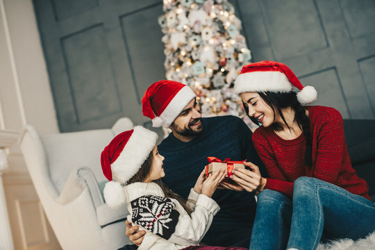 Present for mom. Happy Christmas family at home near ornate festive Xmas tree, Celebrating Holidays and congratulates earch other