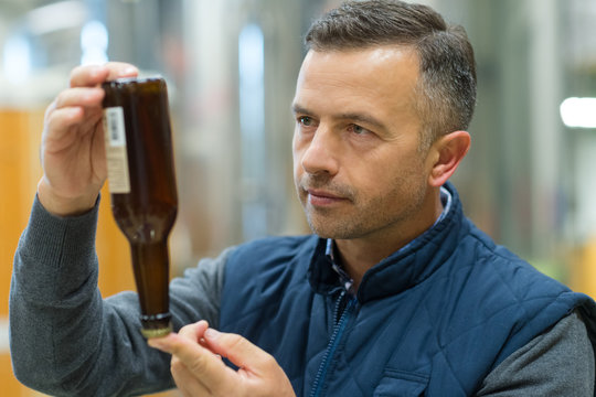 Man inspecting beer bottle in factory