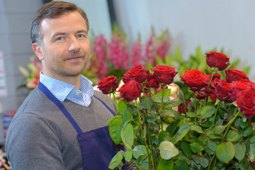 Male florist holding bouquet of red roses