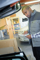 Obraz premium Mechanic checking packages against delivery slip