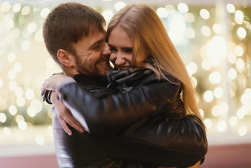 An attractive couple in love embrace and enjoy an intimate moment together, against the backdrop of city lights