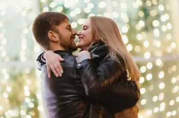 An attractive couple in love embrace and enjoy an intimate moment together, against the backdrop of city lights