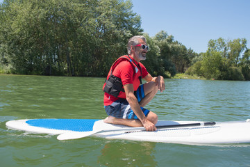 mature attractive rider contemplating nature sitting on paddle board