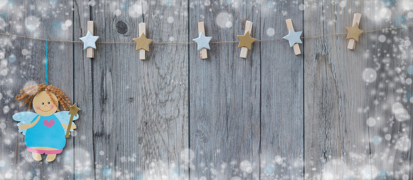 Decorated clothespins hanging on the rope with a little christmas fairy and snow around fraime.