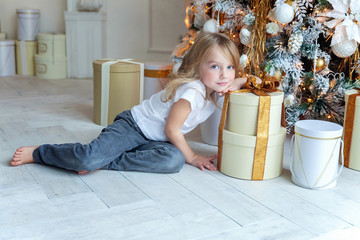 Naklejka premium Young girl opens a gift under a Christmas tree