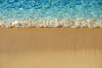 Fototapeta na wymiar Caribbean blue sea ocean wave surf breaking on sand beach with space for copy text photo