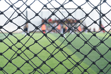 Soccer or football net background, view from on the field with blurred football team.