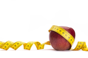 Yellow measure tape around a red apple as a weight loss concept