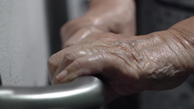 Elderly woman holding handrail while walking