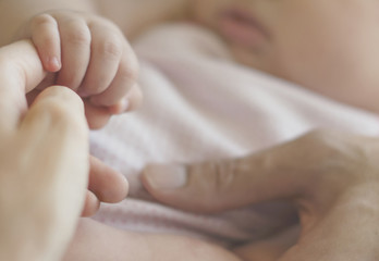 Closeup of baby holding mother hands