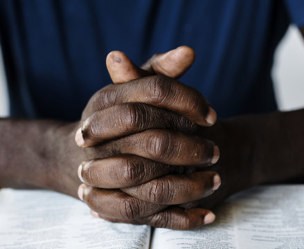 African American male hands resting on an open bible