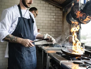 Foto op Aluminium Chef-kok die eten kookt in de keuken van het restaurant © Rawpixel.com