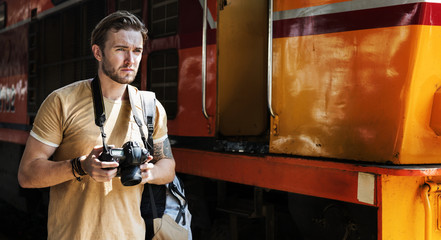 Caucasian photographer at the train station - obrazy, fototapety, plakaty