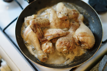 Closeup of chicken meat strips cooking on a hot pan on a gas stove