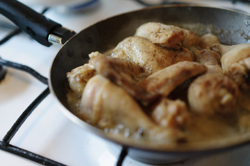 Closeup of chicken meat strips cooking on a hot pan on a gas stove