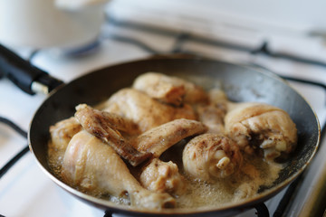 Closeup of chicken meat strips cooking on a hot pan on a gas stove