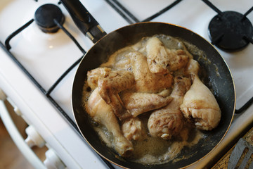 Closeup of chicken meat strips cooking on a hot pan on a gas stove