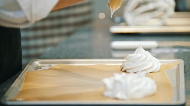 Cooking Pavlova Dessert meringue - pastry tube spread meringue on a baking sheet - macro shot