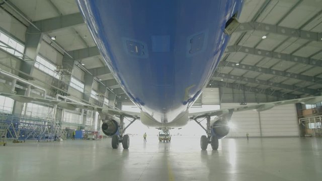 Airplane in hangar, rear view of aircraft and light from windows. Large passenger aircraft in a hangar on service maintenance