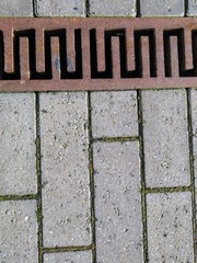 pavement with a rusty old drain grid