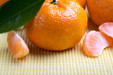 Fresh mandarin orange with green leaves and slices on wooden background