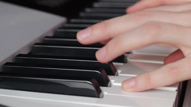 Beautiful fingers on white and black piano keys or a synthesizer play a melody