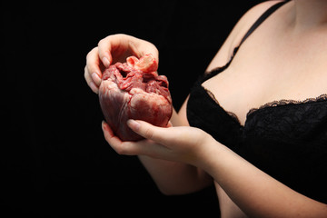 real human heart in beautiful female hands. symbol of love, pain. Insidious nude girl in a bra...