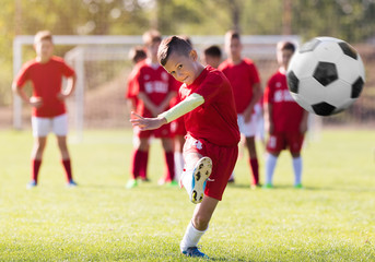Obraz premium Chłopiec kopie piłkę nożną na boisku sportowym