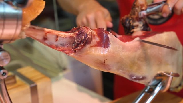Closeup of man cutting Bellota ham with knife