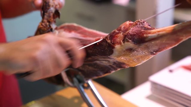 Closeup of man cutting Bellota ham with knife