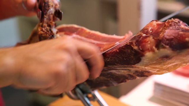 Closeup of man cutting Bellota ham with knife
