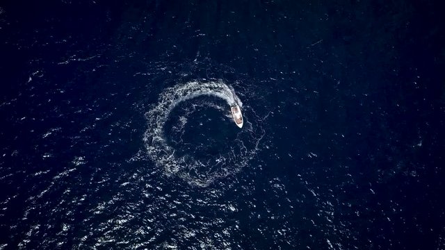 Aerial view of a motor boat designing a circle in the sea navigating fast