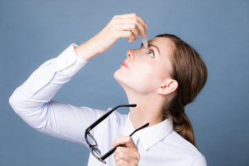 Young woman applying eye lotion.
