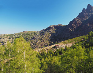 France, Corse, Haut Corse, June 13, 2017: View on refuge Ortu di Piobbu first part of GR 20 famous trek with green birche tree sharp mountain peak and blue sky