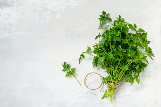 Fresh parsley on a light stone or slate background. Top view with copy space, flat lay.