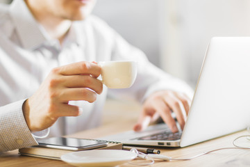 Obraz na płótnie Canvas Man drinking coffee using laptop
