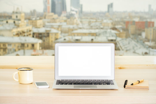Office desktop with empty white laptop