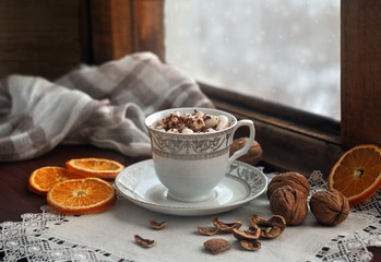 A cup of coffee with a marshmallow on an old wooden snow-covered window. Still life. Christmas and...