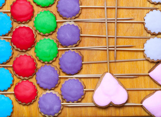 Gingerbread cookies with colored mastic on sticks on the old wooden cutting board