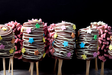 Homemade tiny desserts - banana in chocolate for children's birthday on a dark background
