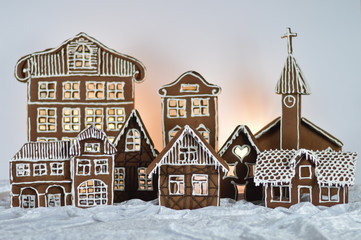 home made gingerbread village in front of white background on white snowlike velvet as decoration...
