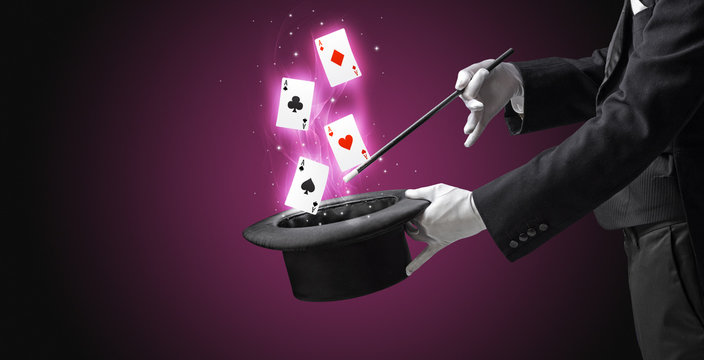 Magician making trick with wand and playing cards