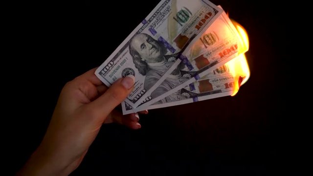 Burning dollars in a hand close-up on a black background